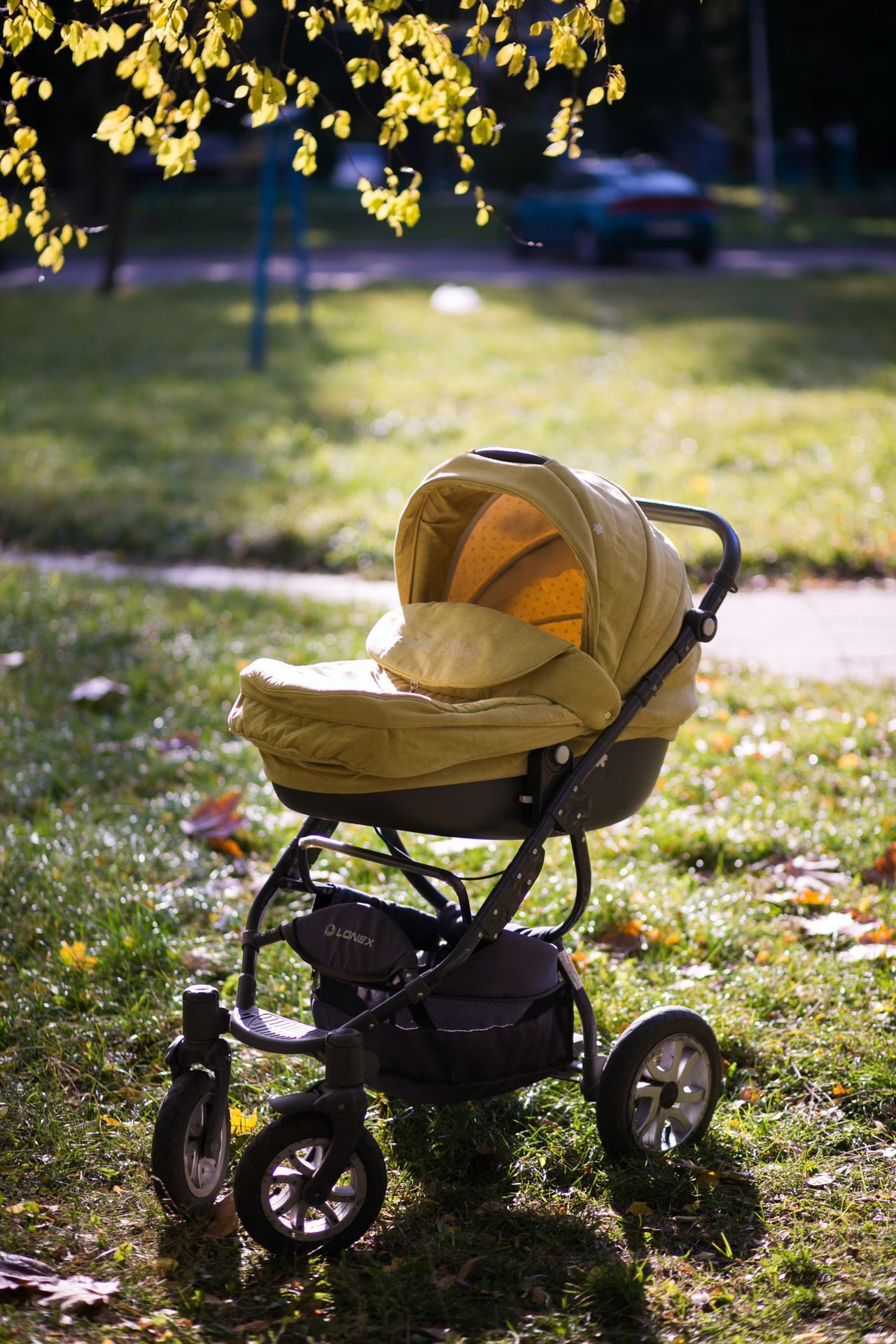 An empty yellow stroller standing in a grassy park