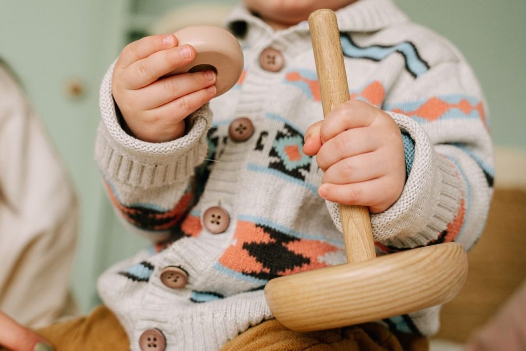 A close view of a small child holding a wooden toy